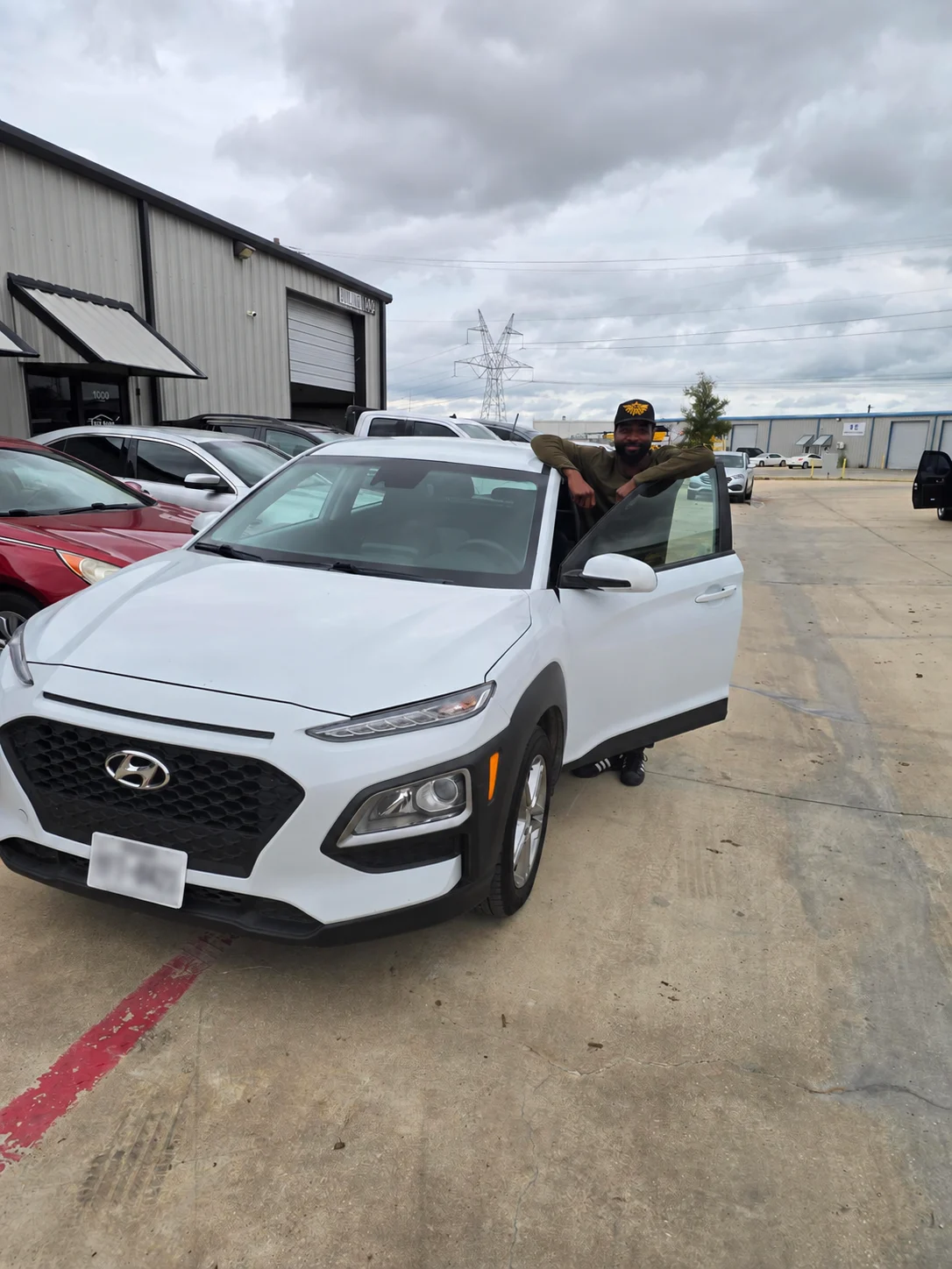 A smiling customer beside a white Hyundai at Top Gear Auto Sales.